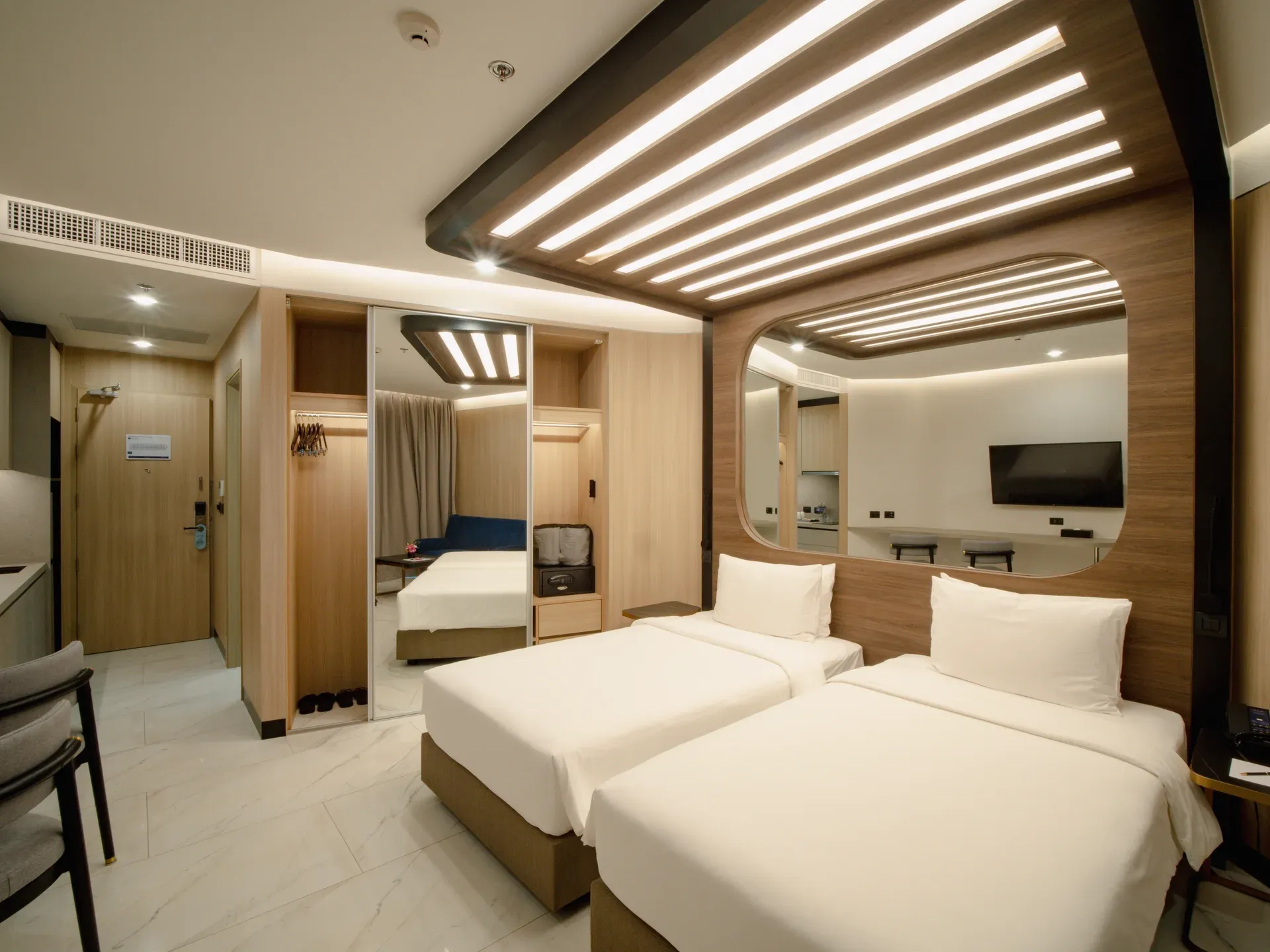 A modern Sole Mio Deluxe Twin room with two beds, marble floors, and warm lighting in Phuket