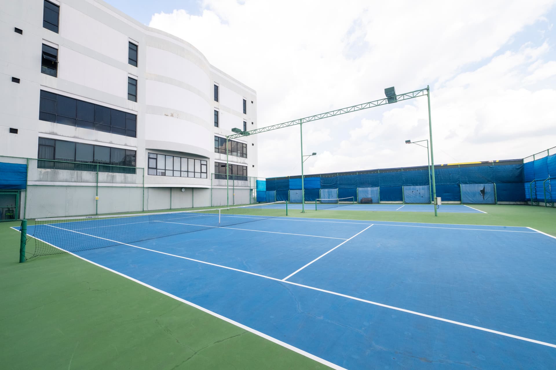 Outdoor tennis court surrounded by gardens